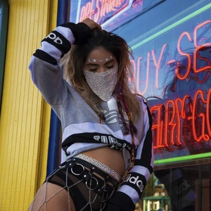 Close-up of trendy rhinestone face mask and metal body chain on streetwear outfit