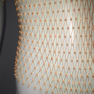 Close-up of white mesh fabric with shimmering rhinestones on a stylish fishnet top
