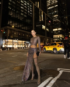 Detail of shimmering rhinestones on mesh long sleeve top and high slit skirt outfit