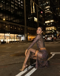 Close-up of sparkling rhinestones on sheer black mesh party top and high slit skirt set