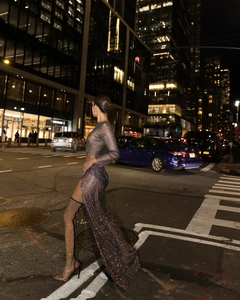 Detailed view of shimmering rhinestone mesh crop top with matching high slit skirt and boots