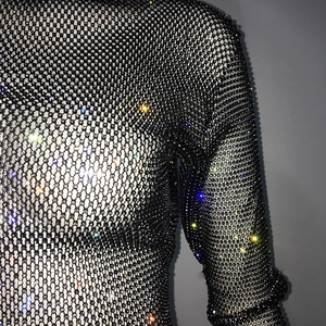 Detail of black mesh top with dense sparkling rhinestones and long sleeves