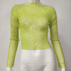 Macro detail of fluorescent green fishnet top with sparkling rhinestones and long sleeves