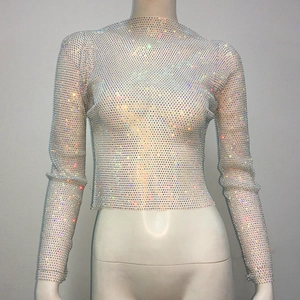 Close-up of sparkling iridescent rhinestones on a white sheer mesh long sleeve crop top