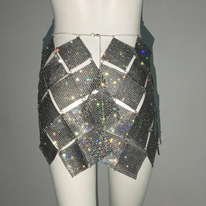 Détail de la jupe en maille métallique strassée montrant des patchs brillants et une chaîne