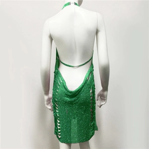 Dettaglio mini abito verde con paillettes, schiena scoperta e fianchi traforati intrecciati