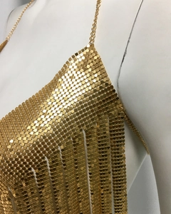 Détail du haut à paillettes dorées avec plaques hexagonales et ourlet à franges