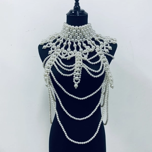 Detailed close-up of luxury white faux pearl body chain shawl with intricate mesh draping