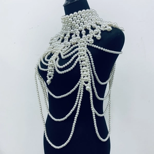 Detail of layered white pearl body chain with fringe shawl design on black mannequin
