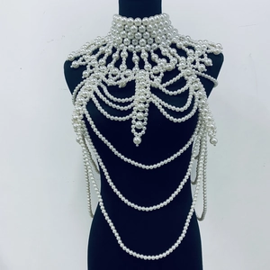 Close-up of elegant white faux pearl body chain with layered fringe on a black mannequin