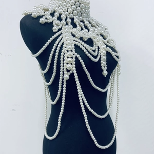 Close-up of elegant multi-layered white pearl body chain and tassel shawl on a black bust