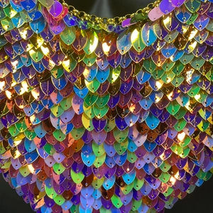 Vue macro de paillettes irisées et maillons de chaîne dorés sur un haut de fête brillant