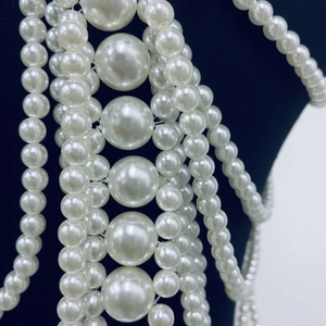 Detail of multi-layered cream white pearl body chain with fringe on a black mannequin