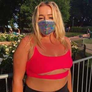 Détail du masque à paillettes argentées et du crop top rose ajouré sous la lumière