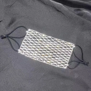 Vue macro du masque en maille strass argentée sur satin noir montrant des détails brillants