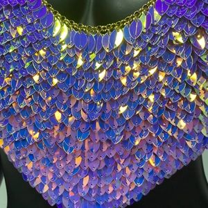 Gros plan de paillettes violettes irisées et chaîne dorée sur un haut sexy de type chaîne