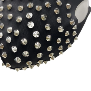 Vue macro d'un masque punk avec des clous argentés sur un tissu noir élastique