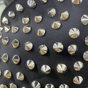 Gros plan des rivets métalliques argentés sur un tissu noir au style punk chic