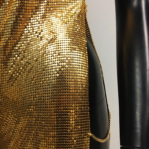 Close-up of golden metallic chainmail dress with reflective sequin texture details