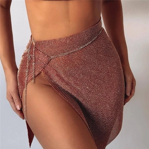 Détail d'une mini-jupe en strass or rose avec fente latérale et chaîne de taille argent