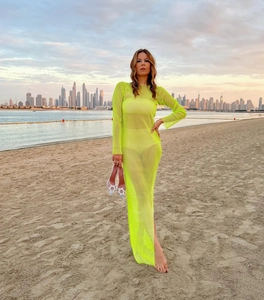 Detail of neon green mesh long sleeve dress showing fishnet texture on beach