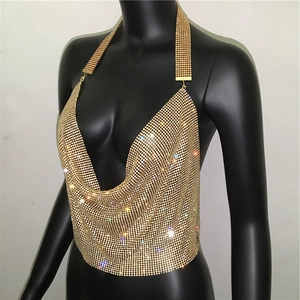 Dettaglio del crop top in maglia di paillettes dorate con scollo a V profondo e scollo