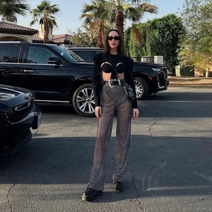 Dettaglio dei pantaloni a rete grigi con strass e cintura in pelle nera con fibbia trendy