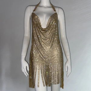Détail de robe dos nu dorée avec strass, décolleté plongeant et bas à franges