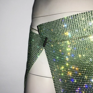 Détail d'un haut de clubbing en maille de strass vert émeraude avec des maillons en métal