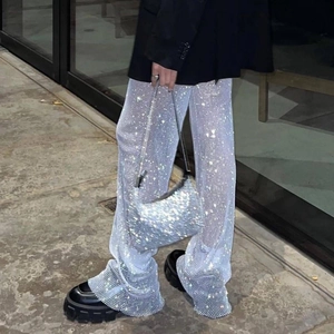 Dettaglio dei pantaloni a rete con strass scintillanti e borsa argentata coordinata