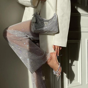 Dettaglio di pantaloni in rete di strass argento con tacchi decorati da fiocchi di cristallo