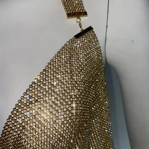 Détail de la maille métallique dorée avec strass brillants et boucle de fermeture au cou