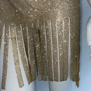 Gros plan des pompons en strass étincelants et du tissu en maille dorée de la robe