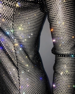 Close-up of black fishnet fabric with dense colorful rhinestones on elastic mesh dress