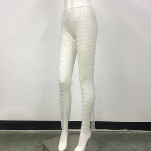 Detail of white fishnet pants with sparkling rhinestones and transparent mesh texture
