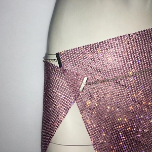 Détail d'une jupe portefeuille en résille rose avec strass brillants et chaînes