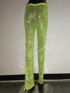 Dettaglio dei pantaloni a rete verde neon con strass scintillanti e tessuto a maglia fine
