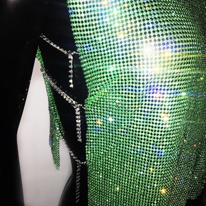 Detail of green rhinestone mesh top featuring intricate side metal chains and tassels