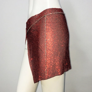 Détail d'une mini-jupe rouge étincelante en strass avec fente latérale et texture maille