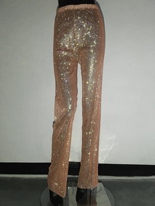 Dettaglio dei pantaloni in rete color oro champagne con strass lucidi per feste