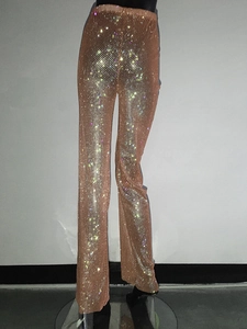 Dettaglio macro dei pantaloni in rete con strass a vita alta e cristalli scintillanti su tessuto nude