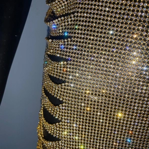 Dettaglio ravvicinato del tessuto in maglia metallica dorata con strass luccicanti