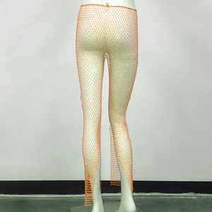 Macro view of orange rhinestone fishnet trousers showing detailed mesh with sparkling stones