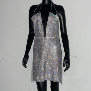 Détail de la robe courte dos nu à paillettes argentées avec décolleté plongeant et tissu brillant