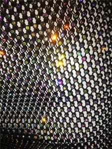 Detail of black mesh fabric with rainbow rhinestones and intricate netting structure