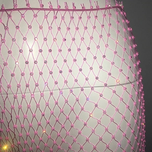 Detail of pink rhinestone mesh fabric with sparkling crystals on elastic fishnet pants