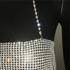 Detailed close-up of sparkling rhinestone mesh and metal chain links on a sexy camisole top