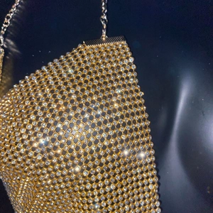 Détail d'une robe en maille métallique dorée avec strass brillants pour soirée