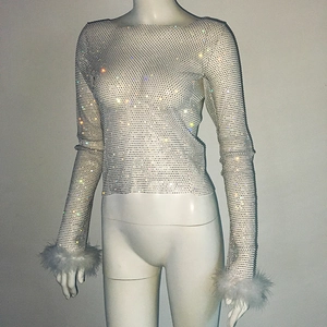 Detail of white mesh top with shimmering rhinestones and elegant feather cuffs