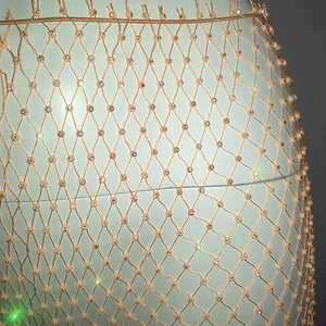Close-up of beige rhinestone fishnet fabric with sparkling crystals on a mannequin